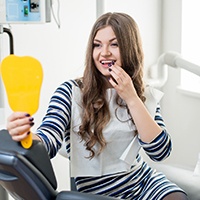Woman looking at her smile in dental mirror.