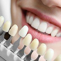Closeup of patient's smile compared with tooth color chart