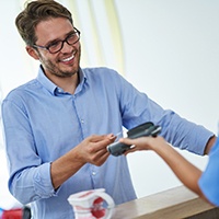Man using credit card to pay for dental treatment